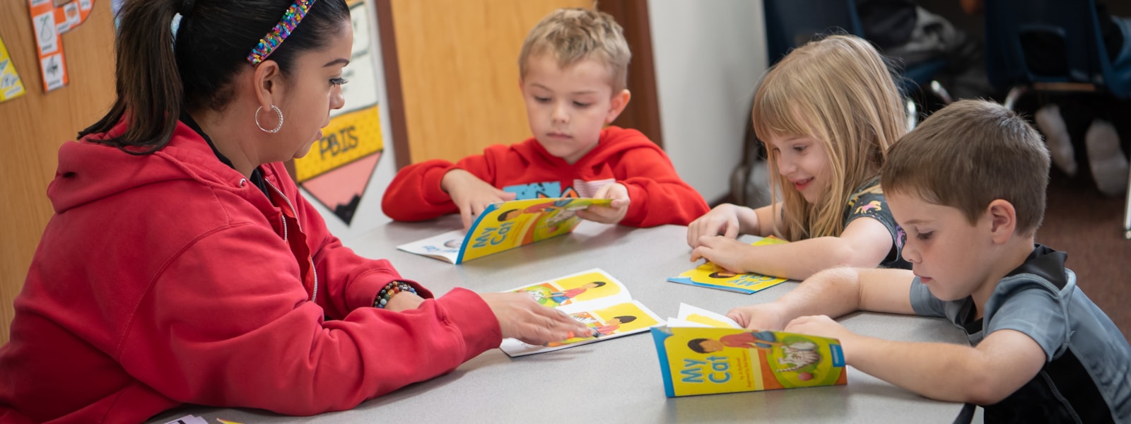 Kindergarten students learning how to read with a teacher