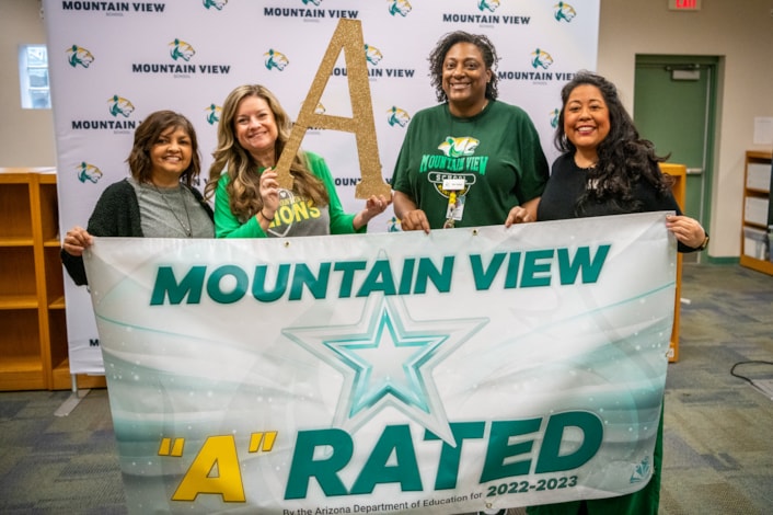 teachers holding "A" Rated Banner