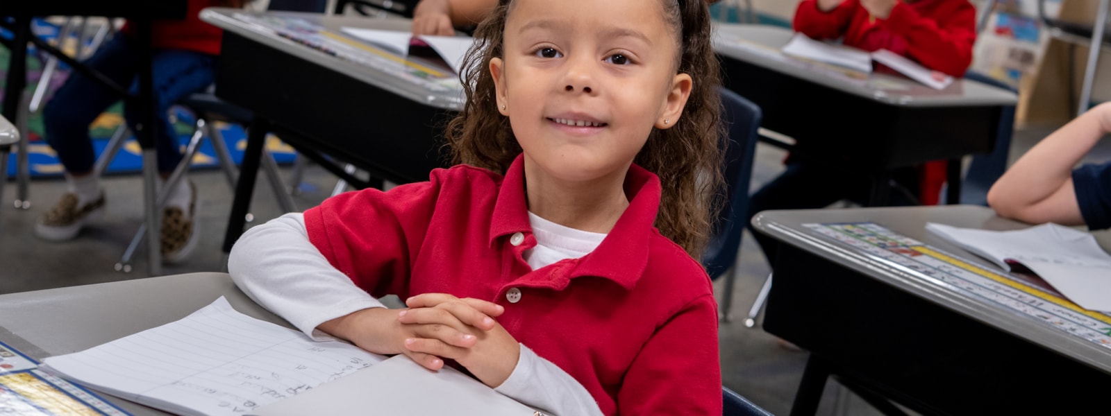 Kindergarten student sitting at desk smiling