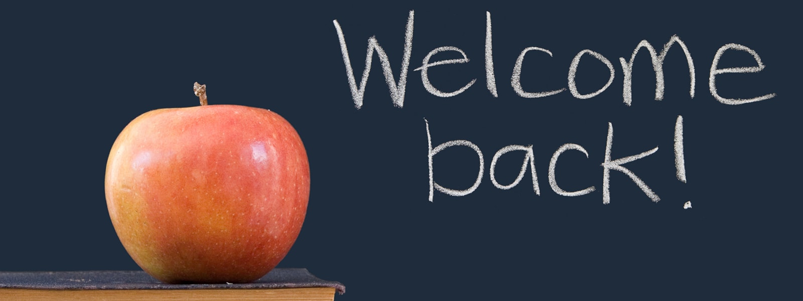 Welcome Back written on a chalkboard with an apple