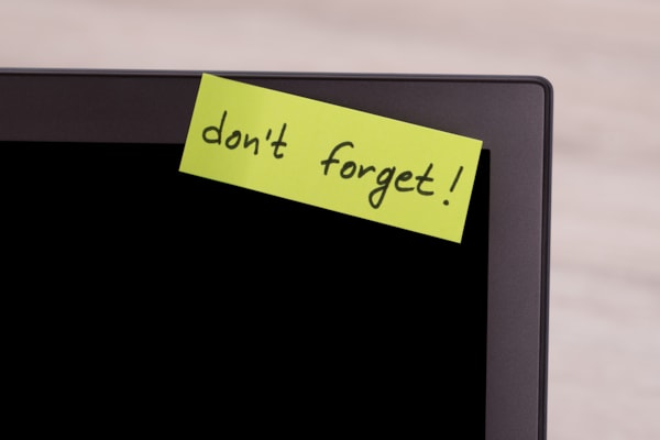 Computer screen with yellow sticky saying Dont forget
