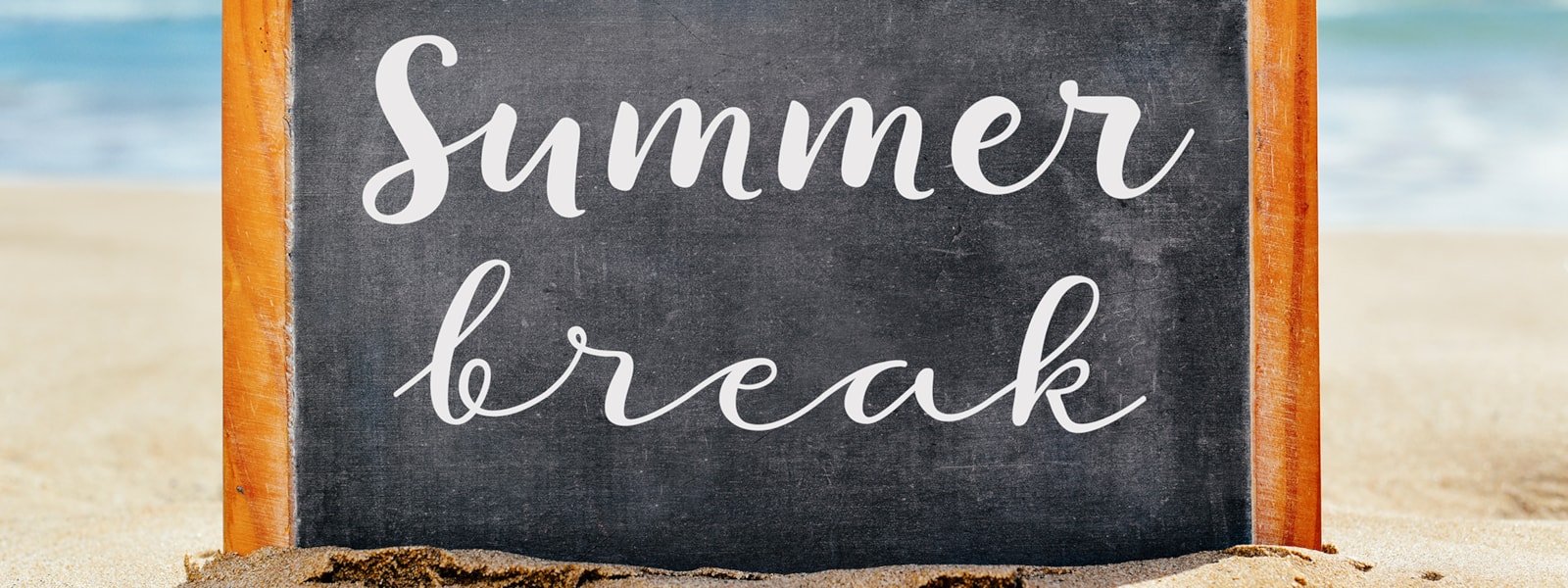 chalkboard saying 'Summer break' on beach