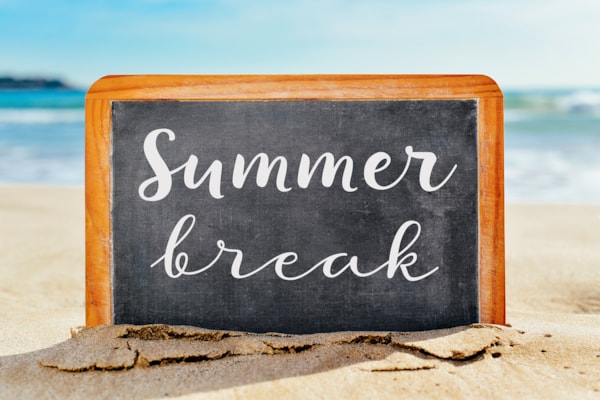 chalkboard saying 'Summer break' on beach