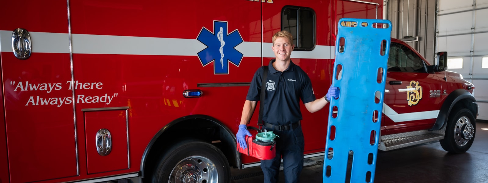 EMT holding equipment in front of ambulance