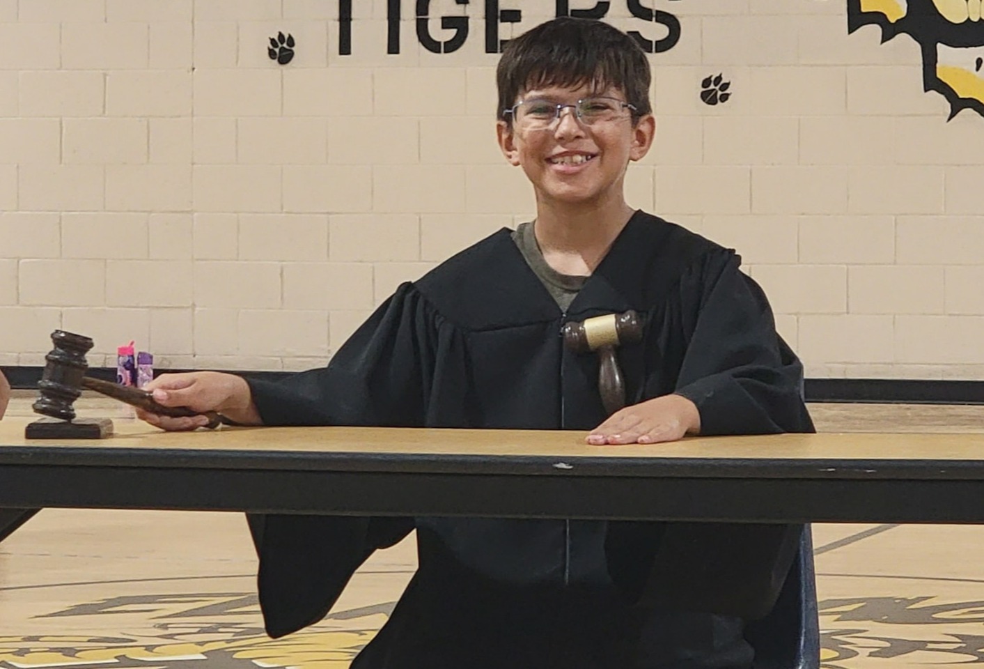 Student wearing the judges robe and holding the gavel.