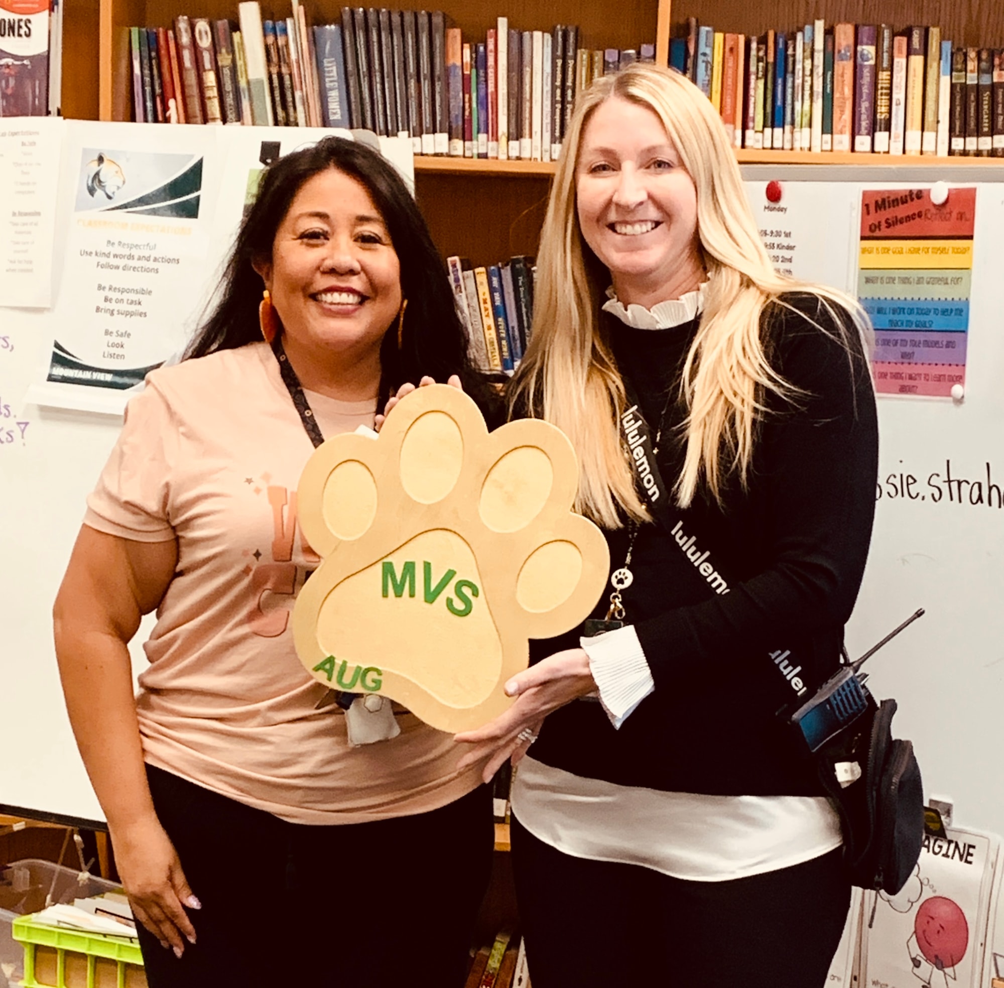 Picture of Winner Monica Rodriguez standing in front of library books with Principal Cruz and a Golden Paw