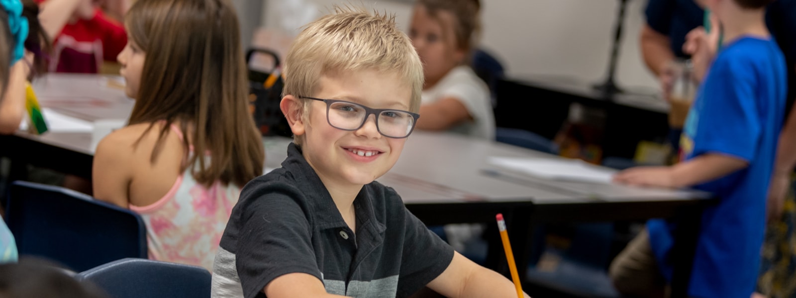 Student in a classroom smiles for the camera