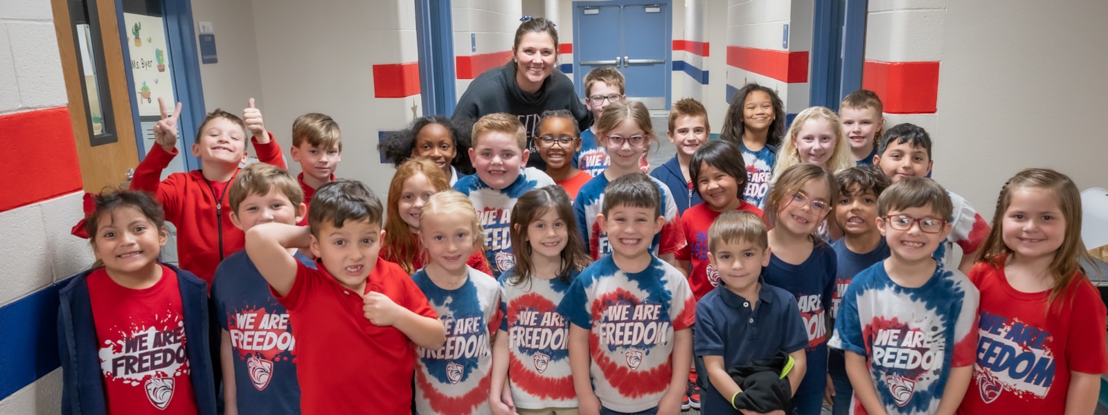 Students and teacher smiling for camera